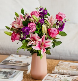 Vibrant floral arrangement featuring pink lilies, roses, and purple blooms in a chic vase.
