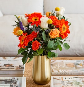 Vibrant floral arrangement featuring orange gerbera daisies and white roses in a chic vase.
