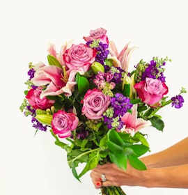 Vibrant bouquet featuring pink roses, lilies, and purple flowers, ideal for celebrations.