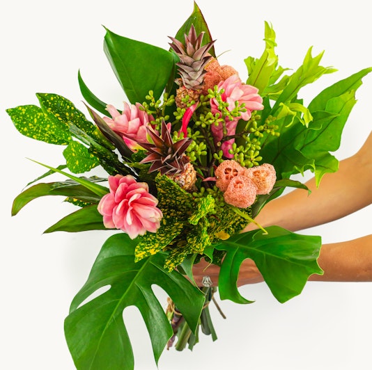 Vibrant tropical bouquet featuring pink flowers and lush green foliage, perfect for celebrations.