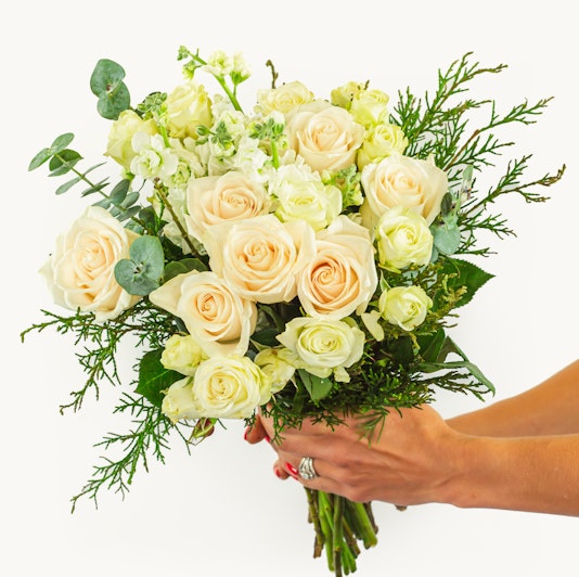 Elegant bouquet of cream roses and white flowers, accented with greenery. Perfect for any occasion.