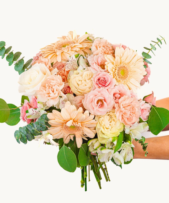 A lovely pastel bouquet featuring roses, gerbera daisies, and lush greenery.