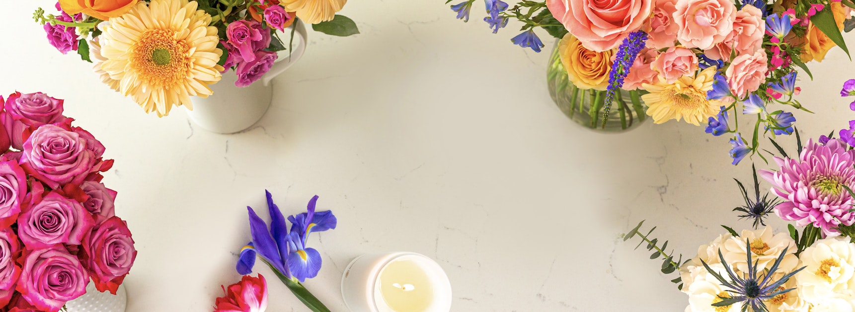 Vibrant floral arrangement featuring pink roses, daisies, and colorful blooms in chic vases.