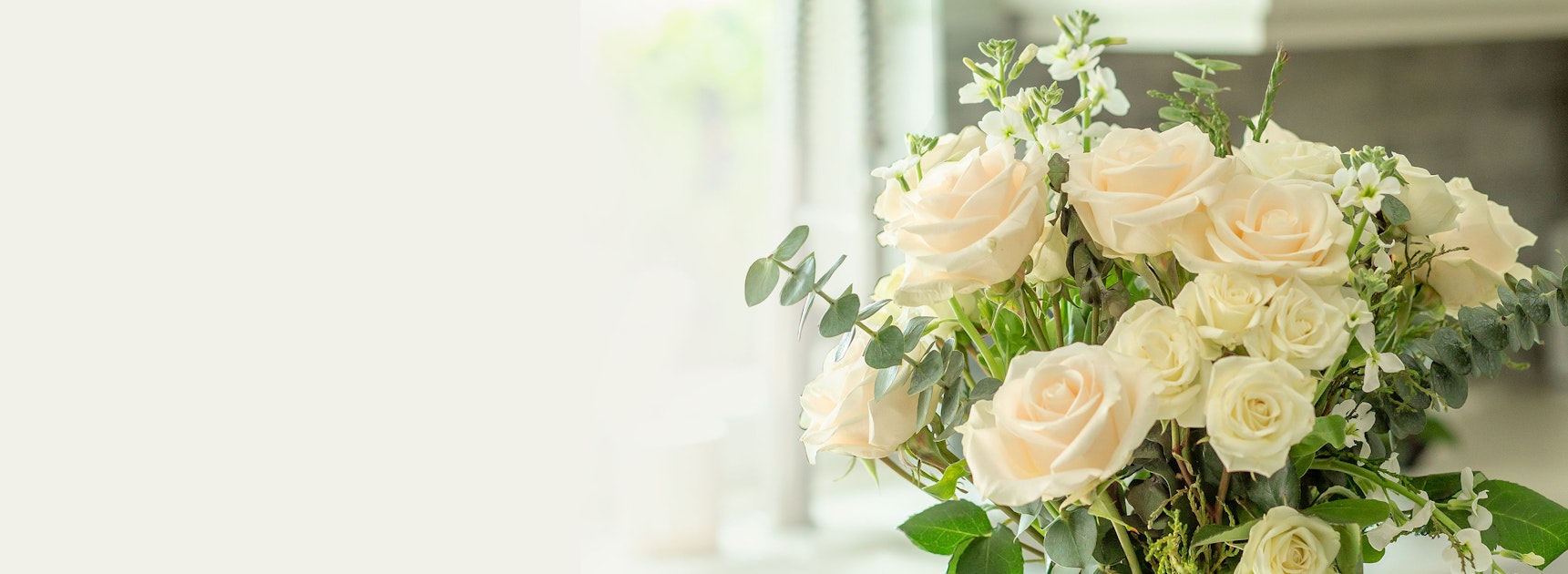 Elegant bouquet of soft pink and white roses, accented with lush greenery.