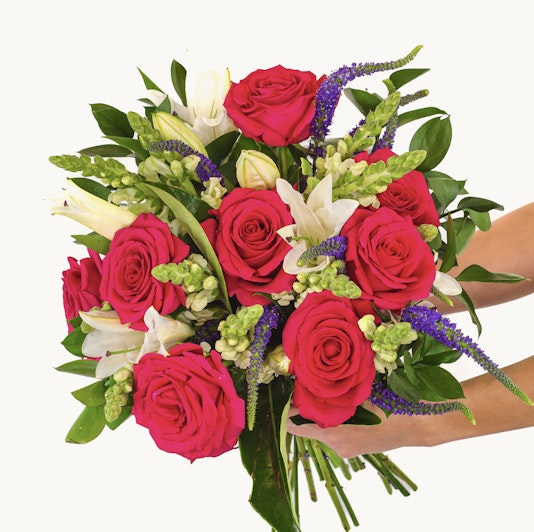 Vibrant bouquet of pink roses, white lilies, and green foliage, perfect for any celebration.