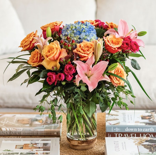 Vibrant floral arrangement featuring roses, hydrangeas, and lilies in a chic glass vase.