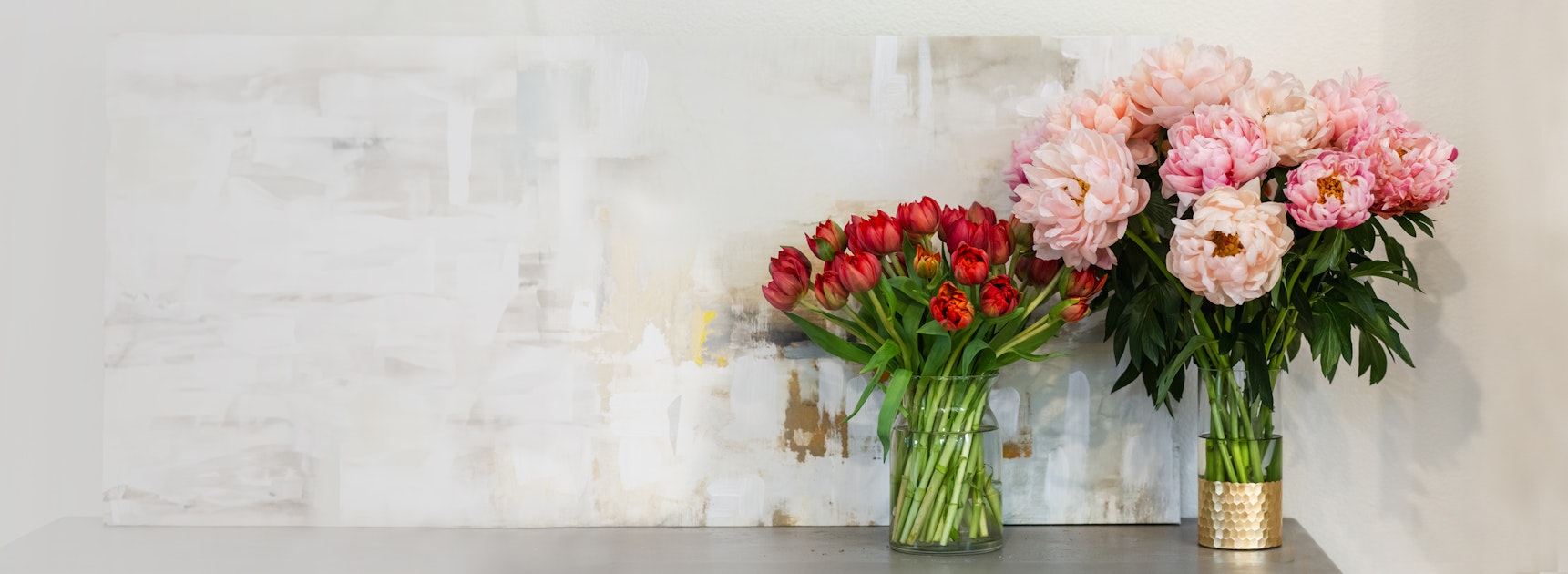 A vibrant arrangement of red tulips and soft pink peonies in decorative vases, enhancing any space.