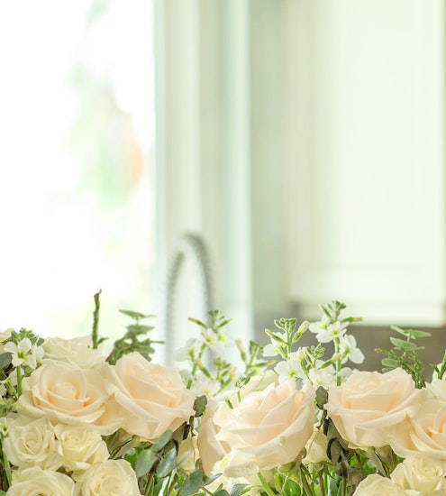 Delicate arrangement of soft peach roses and white flowers, ideal for elegant decor.