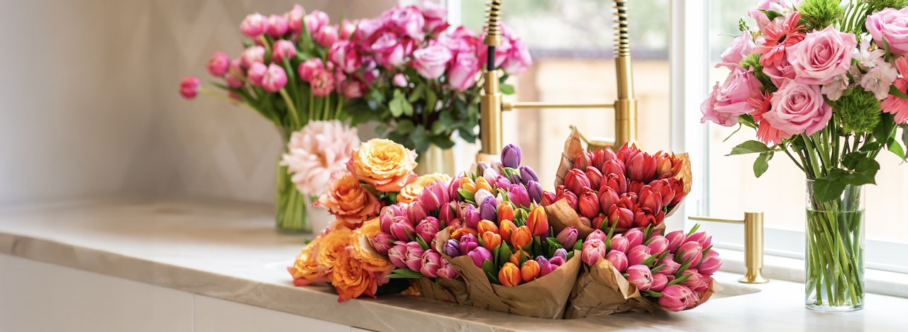 Vibrant assortment of tulips and roses displayed in a sunlit floral arrangement.