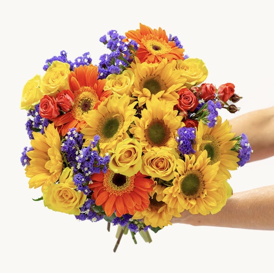 Vibrant bouquet featuring sunflowers, roses, and seasonal blooms in a cheerful arrangement.