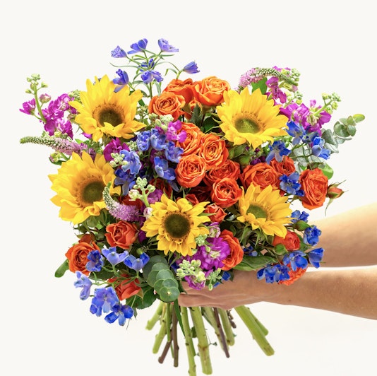 Bright floral bouquet featuring sunflowers and vibrant roses in assorted colors.