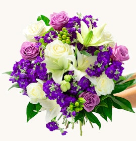Vibrant bouquet featuring white lilies, purple roses, and lush greenery, ideal for celebrations.
